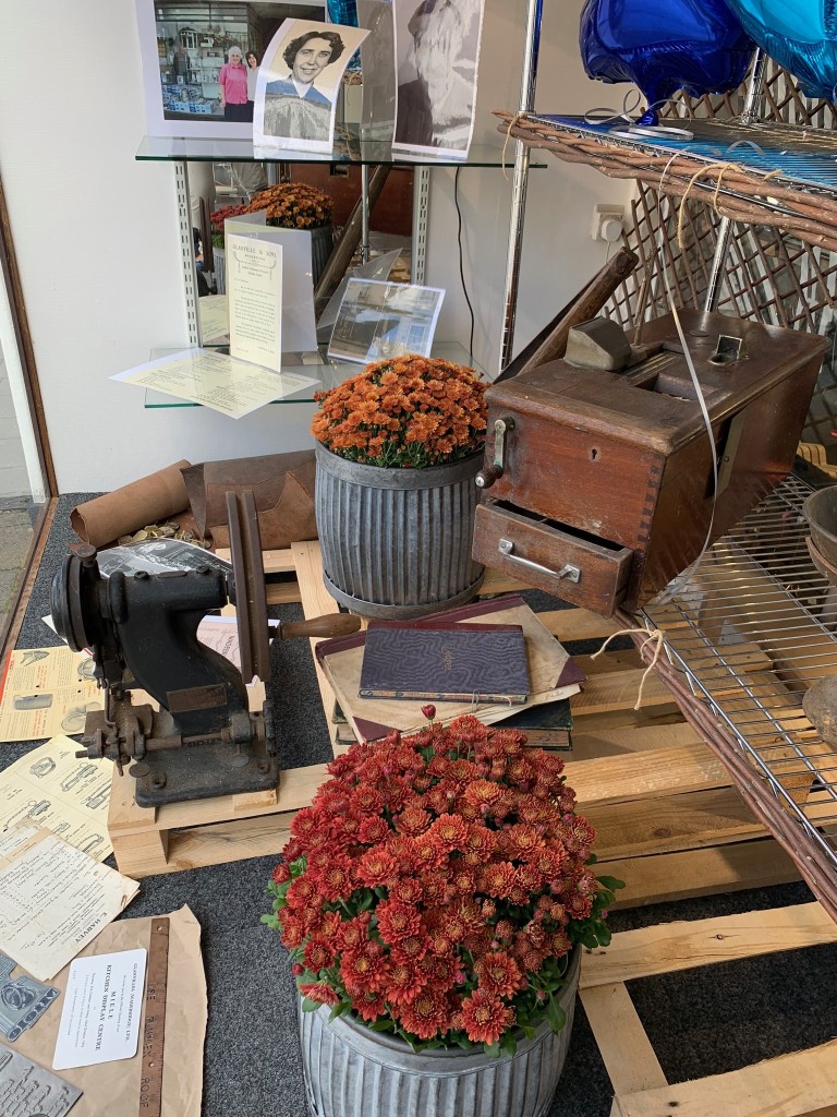 Above: Part of Glanvilles window display showed objects from the store’s history. They include a wooden till, scale, a sewing machine, decimal conversion chart and the original sales ledger book.