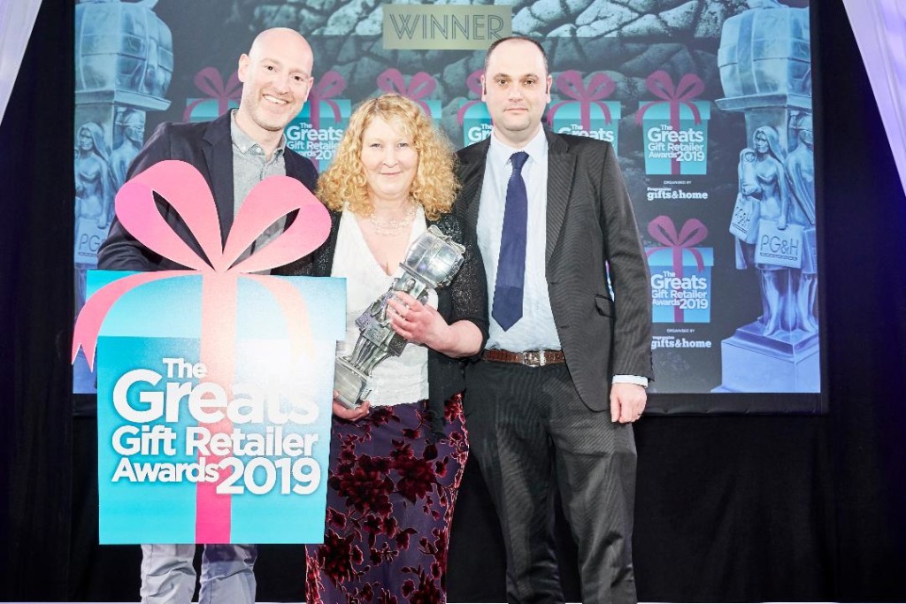 Above: William of Audlem’s owner Judy Evans is shown receiving the Independent Gift Retailer of the Year North & Northern Ireland trophy at The Greats Awards in 2019. On Judy’s right is David Cree, sales manager at Joe Davies, which sponsored the category. Also shown is Greats Awards compere. comedian Henry Paker.